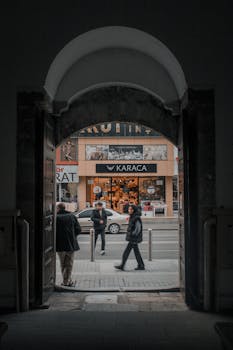 People walking and interacting near a shop entrance in a downtown urban street scene.