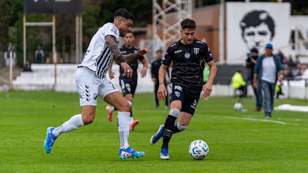 Two football players in intense action during a lively match on a lush green field.